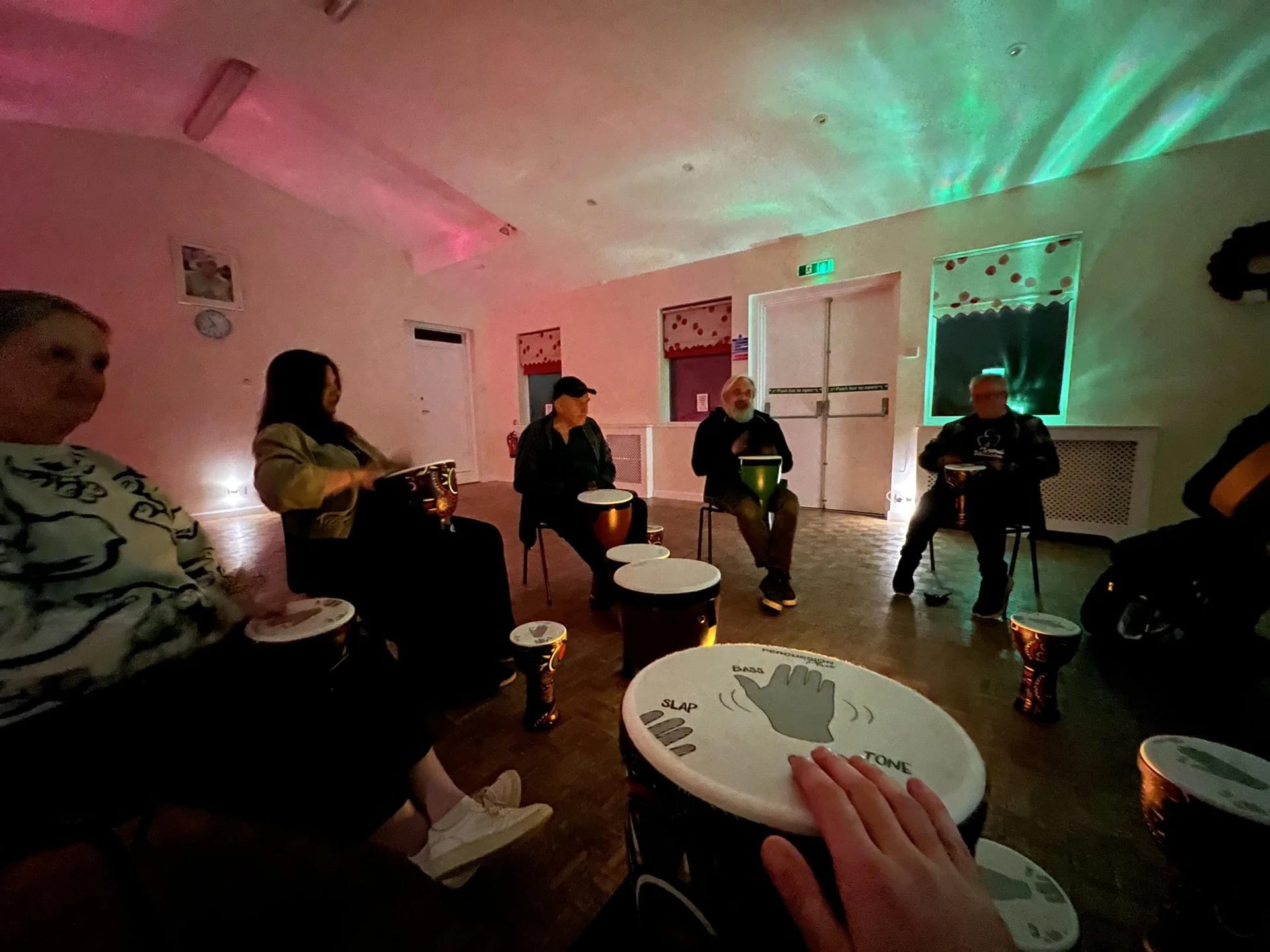 Participants in a drum circle playing djembes together