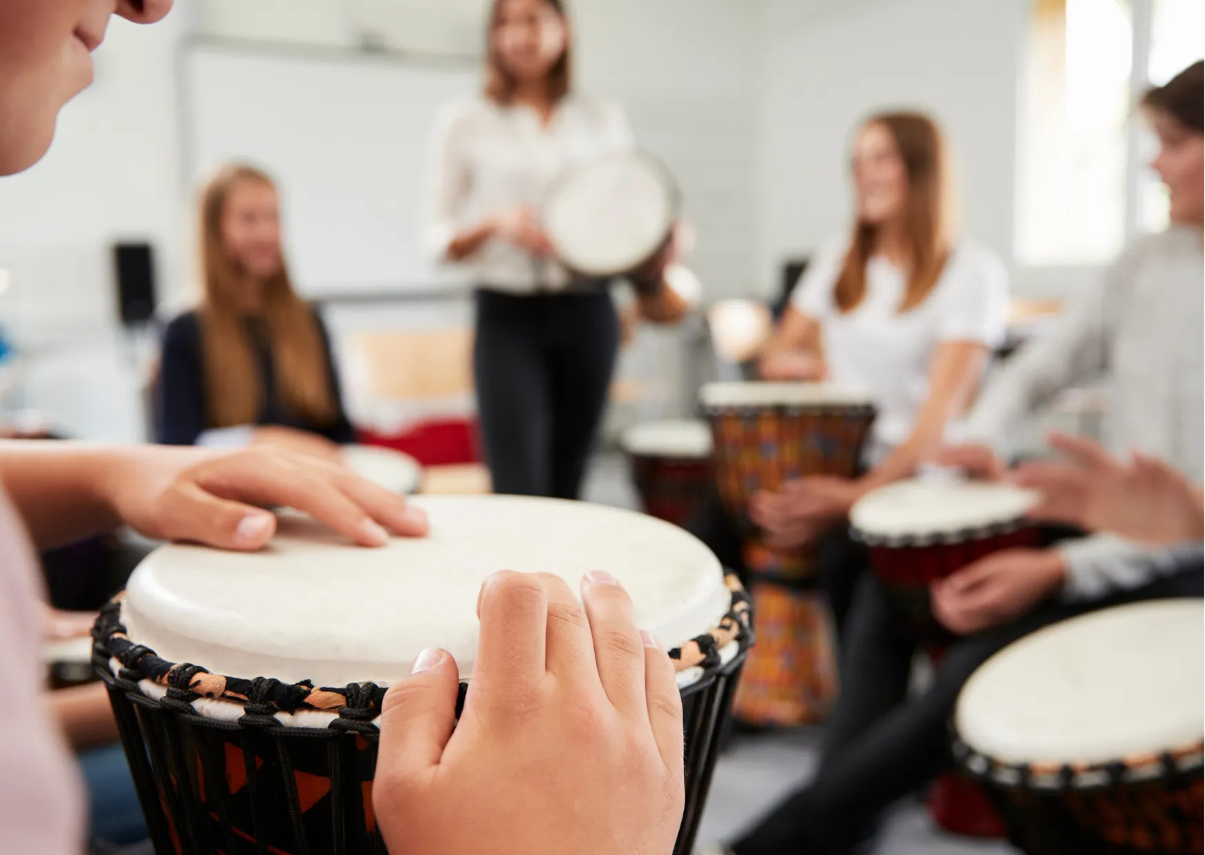 Young people playing djembes during a school drumming workshop